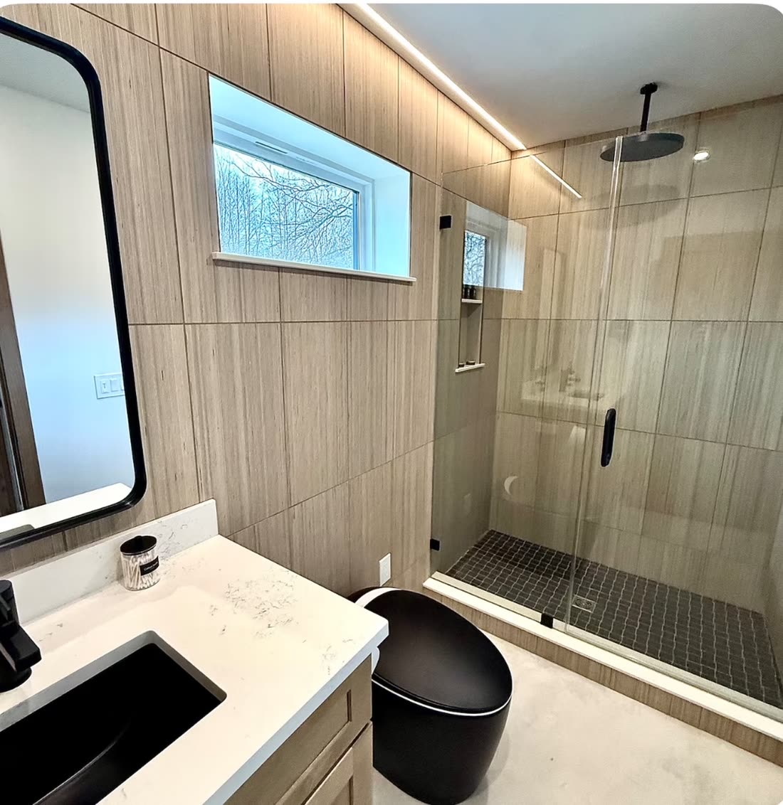 Spa-style primary bathroom remodel with a glass-enclosed shower, wood-look tile, and quartz vanity.