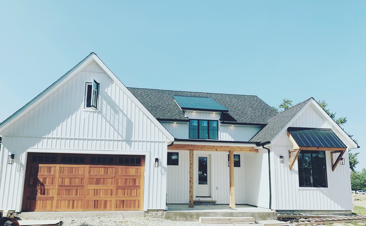 Modern white farmhouse-style home exterior with board-and-batten siding and a wood garage door.