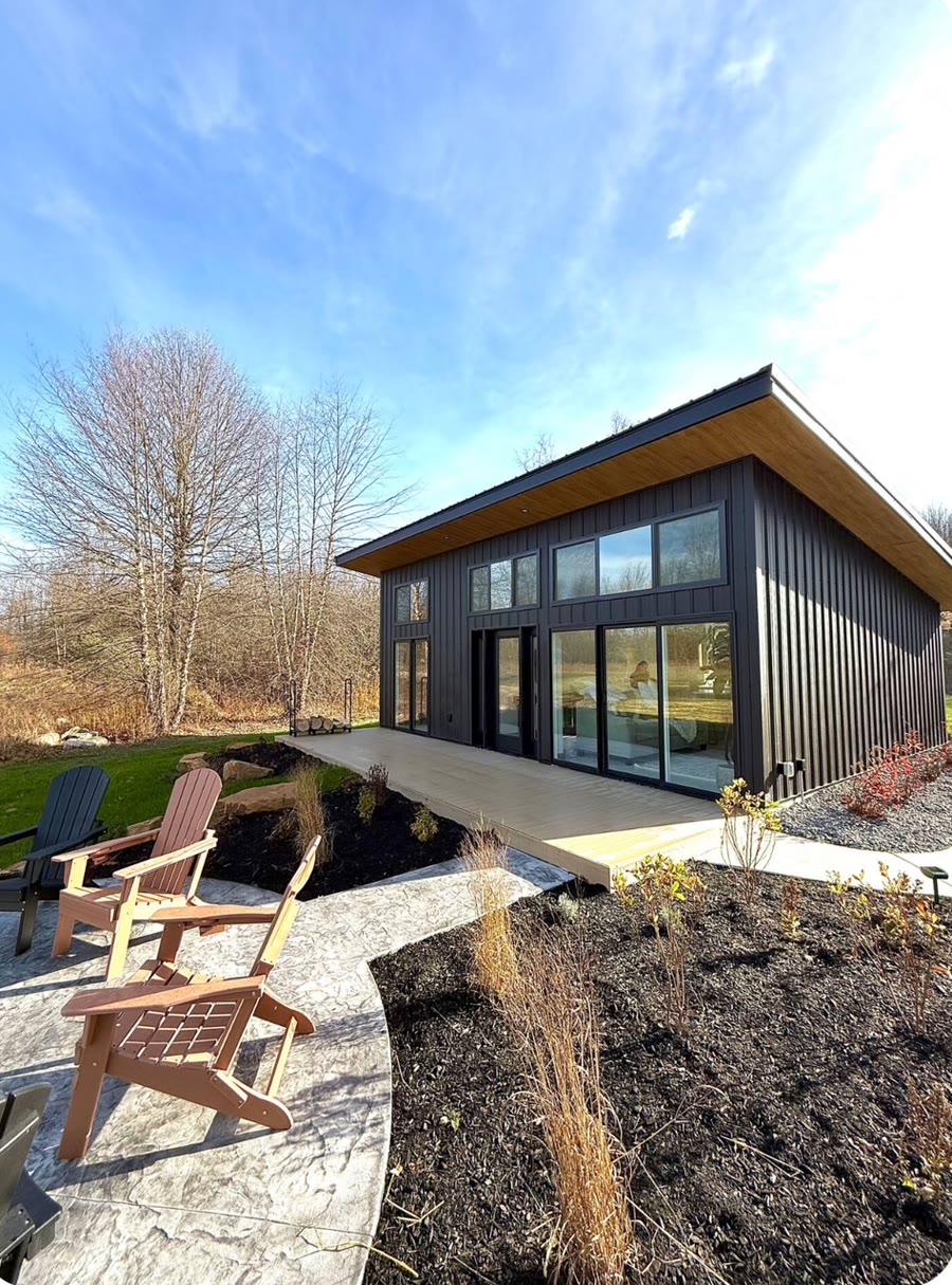 Contemporary home exterior with black vertical siding, a covered porch, and stone accents.